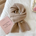 Detailed texture of beige rib-knitted winter scarf with brand tag on soft fabric background - Coffee
