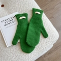 Detailed knit texture of green wool mittens with a 100% wool label on soft fleece - One Size / Green
