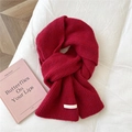 Close-up of vibrant red knitted scarf with soft texture and brand label detail - 21x165cm / Marled Red