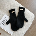 Detail der dicken schwarzen Strickfäustlinge mit weichem Flausch und Markenetikett - Schwarz
