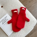 Detail of red mohair knitted mittens with brand label on soft white fleece background - Red