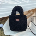 Dettaglio borsa a mano in peluche nero con logo in pelle marrone e tracolla sottile - Nero (3HSM)