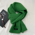 Detail eines grünen 100% Wollschals mit grober Strickstruktur und Materialetikett - Grün
