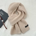Detailaufnahme des 100% Woll-Etiketts auf einem dicken beigefarbenen Strickschal für Winter - Haferflocken