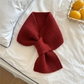 Close-up of red chunky knit scarf with crossover pull-through design on white bedding - Red