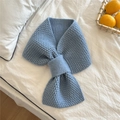 Detail of blue chunky knit scarf with a stylish bow-knot design on white bedding - Light Blue