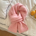 Detailed close-up of pink knit scarf texture with a golden metal tag on white fabric - Pink