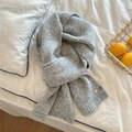 Detail of grey knitted winter scarf featuring ribbed edges and a small metal logo tag - Light Grey