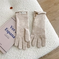Close-up of beige knit gloves with wooden button details and brand label on soft fabric - One Size / Beige Coffee