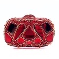 Dettaglio macro di strass in cristallo rosso e cornice dorata su borsa da sera lusso - Rosso