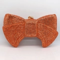 Close-up of orange rhinestone bow evening clutch bag with gold metal frame and clasp - Orange