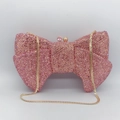 Nahaufnahme der funkelnden Abendtasche mit rosa Strass-Schleife und goldener Kette - Rosa