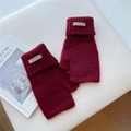 Detail of dark red chunky knit fingerless gloves with a vintage leather brand label - One Size / Burgundy