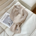 Close-up of knit scarf texture and metal logo tag on a white textured background - Beige