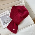 Close-up of red knitted scarf with a small silver metallic tag on white soft background - Burgundy