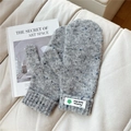 Close-up of gray knitted wool mittens with colorful flecks and a branded woven label - Starry Green Flower Gray