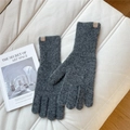 Close-up of gray knit gloves with warm wool texture and brand tag on soft cushion - One Size / Dark Gray