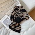 Dettaglio della sciarpa in maglia spessa con motivo zebrato su un divano bianco - Zebra Caffè