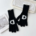 Dettaglio guanto in maglia nera con bordo in ecopelliccia e patch con lettera D - Nero