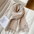 Detailed texture of beige knit scarf with long tassels and small metal brand tag on leather - Beige Coffee