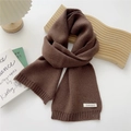 Detail of dark brown knitted scarf with ribbed edges and cashmere label on a cozy setting - Dark Brown