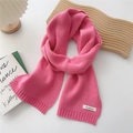 Detailed macro view of vibrant pink knit scarf showing soft cashmere texture and woven label - Pink