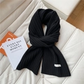 Close-up of black 100% wool knitted scarf with ribbed texture and white wash label - Black