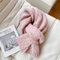 Detalle de bufanda de punto rosa con textura trenzada y etiqueta metálica de marca - Rosa