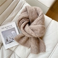 Close-up of thick cable knit texture and brown leather label on light brown scarf - Camel