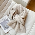 Close-up of beige chunky knit scarf texture with a metallic brand tag on soft surface - Oatmeal Beige