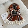 Detail eines Strickschals mit orange-schwarzem Karomuster, Fransen und Markenlabel - Orange Kariert (Doria Dore)