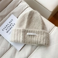Detail of a creamy white knit beanie with soft mohair texture and a minimalist brand label - Beige Splicing Knitted Hat