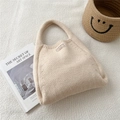 Detail of beige knit tote bag showing vertical texture and brown leather label - Creamy White