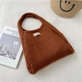 Detail of a brown knit hobo bag with a white woven label on warm textured fabric - Orange