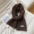 Close-up of a warm dark brown knit scarf with a white brand label on a soft sofa - 20*160cm / Brown