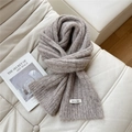 Detail of light coffee knitted scarf with texture and Doria Dore label on a sofa - 20*160cm / Light Gray