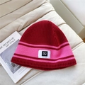 Detail of red and pink striped knit beanie with soft texture and vintage woven label - One Size / Red