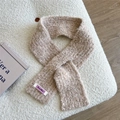 Close-up of beige bouclé knit scarf texture featuring a Jennie Wool woven label - Beige