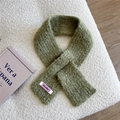 Detailed texture of cross-knitted grass green wool scarf with a woven label on fabric - Green