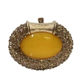Macro shot of oval amber gemstone surrounded by luxury champagne rhinestones on a clutch - Crystal Yellow