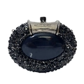Macro detail of black rhinestone clutch with oval gemstone and silver metal clasp - Black