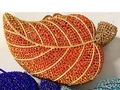 Detail of leaf-shaped evening clutch featuring orange crystals and gold leaf veins - Red