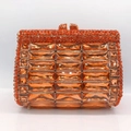 Detailed close-up of orange rhinestones and gold metal frame on luxury clutch purse - Orange