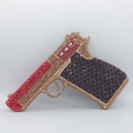 Macro detail of the gun-shaped evening bag featuring red and gold rhinestones - Black Gold Red