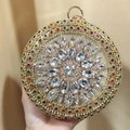 Macro detail of a round evening clutch with colorful rhinestones and gold ring handle - Gold