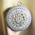 Close-up of circular evening clutch with colorful rhinestones and gold ring clasp - Silver