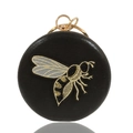 Elegante pochette rotonda in PU nero con ape ricamata e chiusura dorata su sfondo bianco - Nero