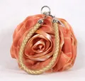 Close-up of orange silk rose clutch bag featuring 3D petal texture and golden woven handle - Gold