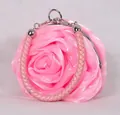 Close-up of pink satin rose evening bag with woven handle and metallic ring detail - Pink