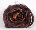 Detailed view of the rose-shaped silk fabric texture and woven shoulder strap on the bag - Coffee